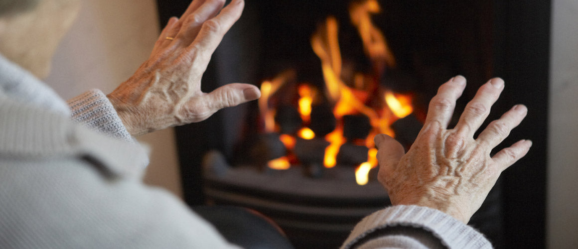 Elderly man warming hands by fire