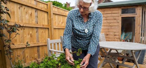 Old person enjoying gardening with a wrist worn personal alarm