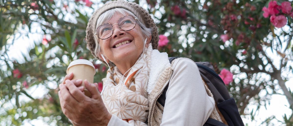 Happy elderly woman having coffee outdoors