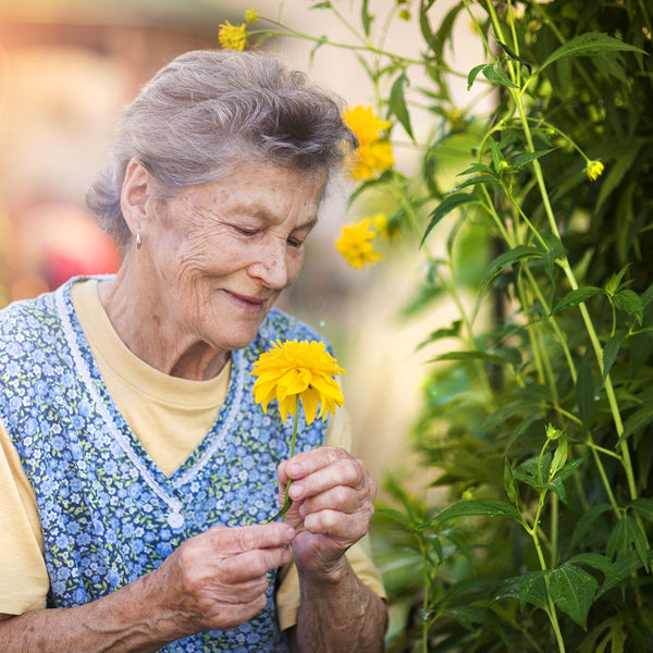 Elderly woman with a colourful flower in her garden