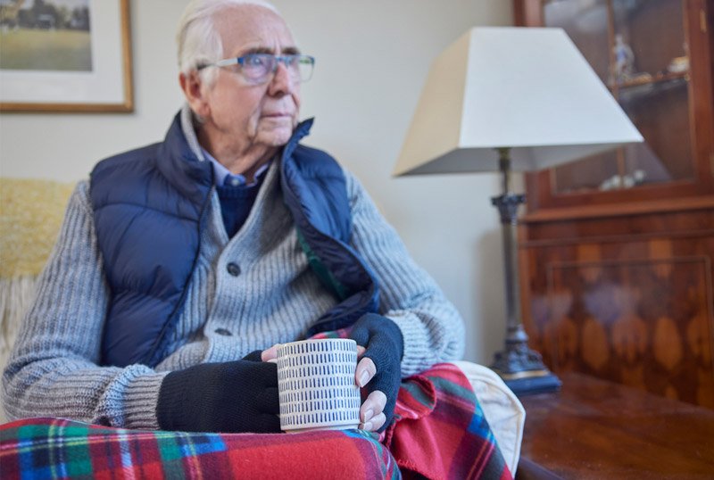 Old man wrapped up warm with hot drink