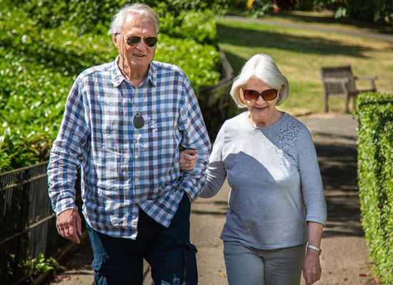 Elderly man wearing falling alarm pendant outdoors