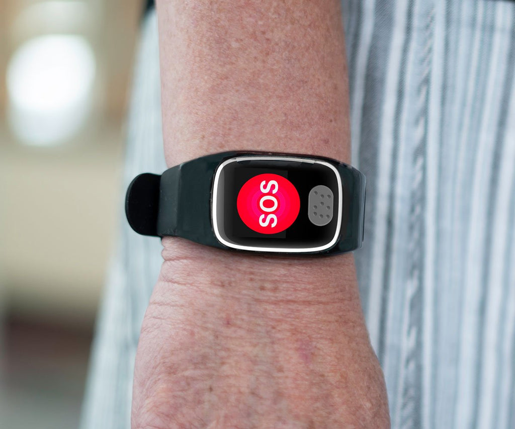 Dementia tracker with SOS button on a wrist against a blurred background
