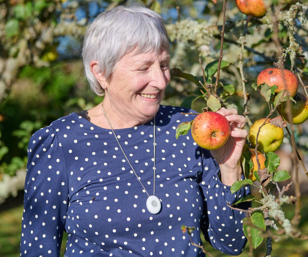 Woman in a blue polka dot dress holding an apple in an orchard