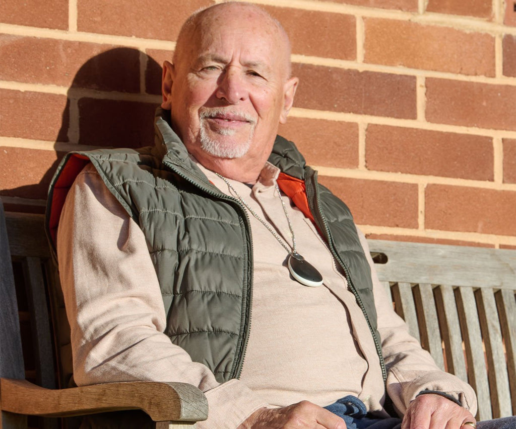 Man sitting on a bench wearing a green vest wearing a personal alarm