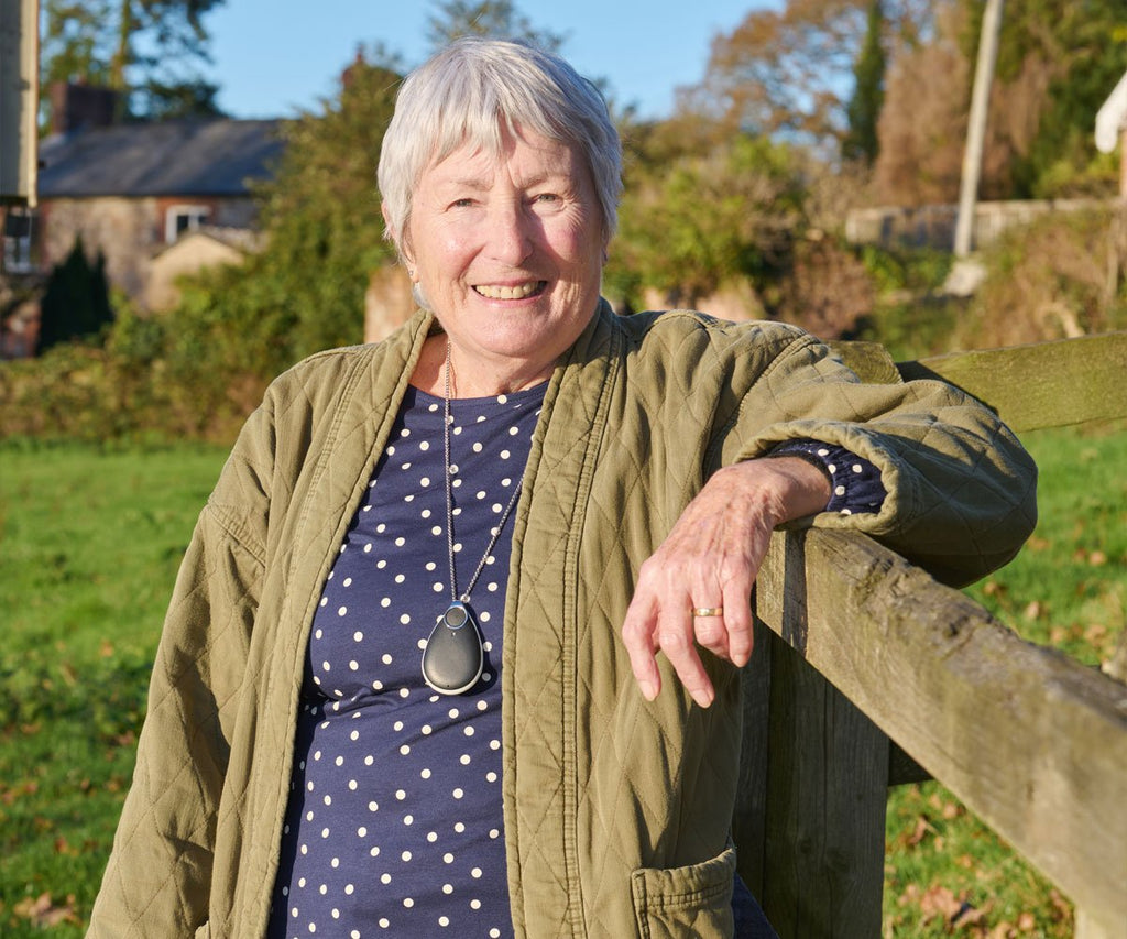 Woman standing outdoors by a wooden fence with a personal alarm