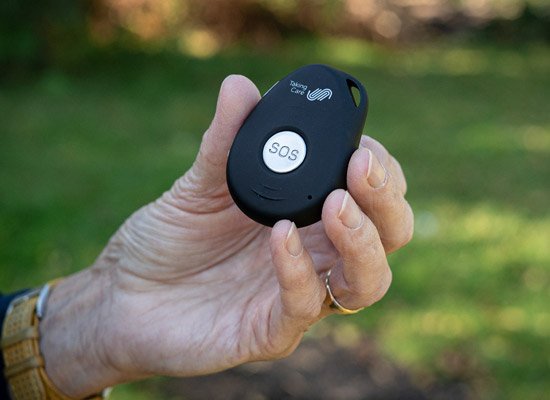 Single button alarm held in hand