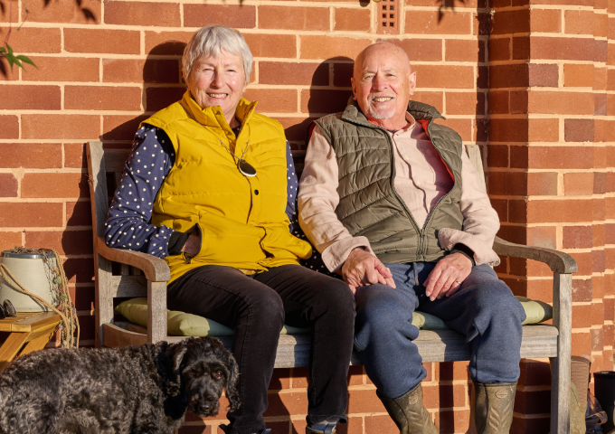 Elderly couple sat on bench wearing GO Fall detection alarm 