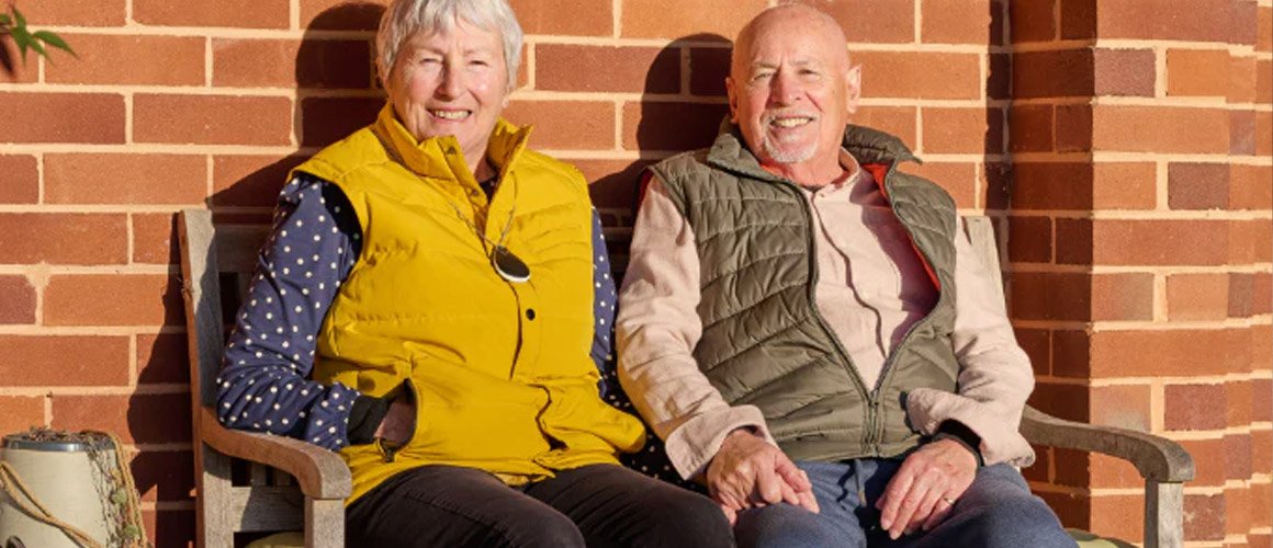 Two older adults sat on a bench