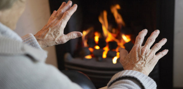 Elderly man warming hands by fire