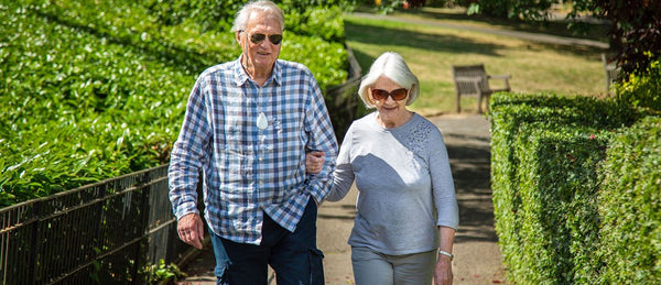 Elderly couple wearing monitored alarm pendants