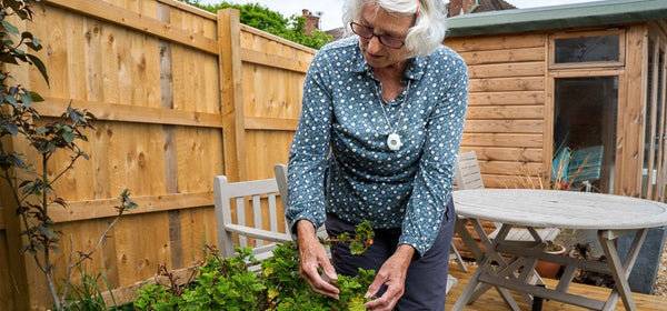 Old person enjoying gardening with a wrist worn personal alarm 