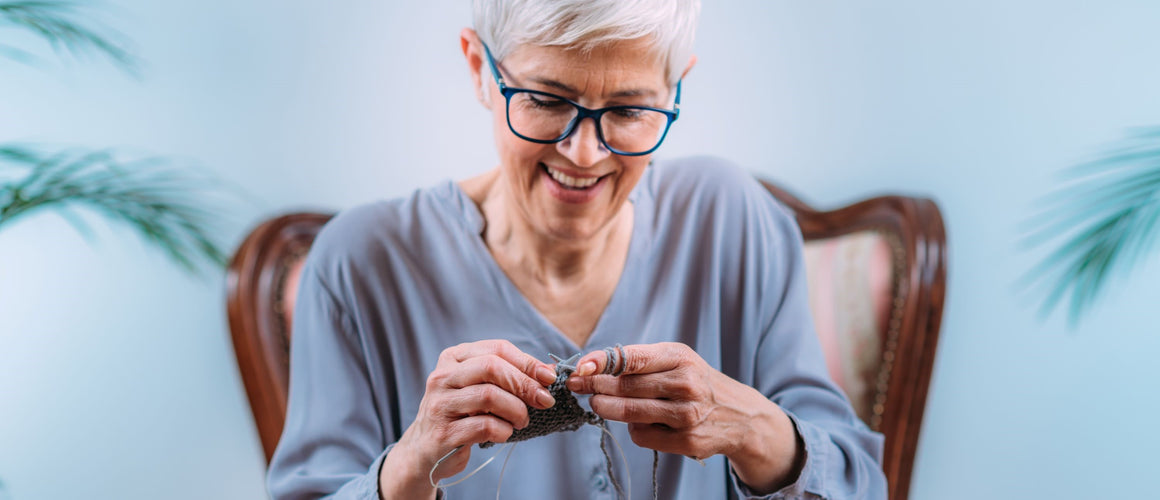 Elderly woman knitting happily