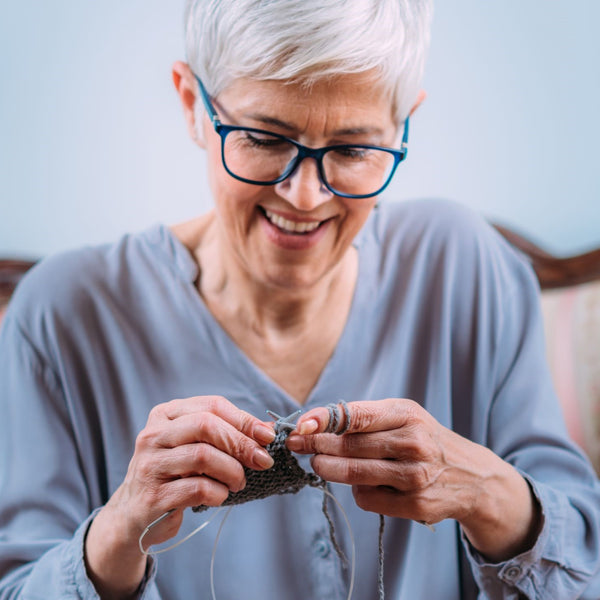 Elderly woman knitting happily