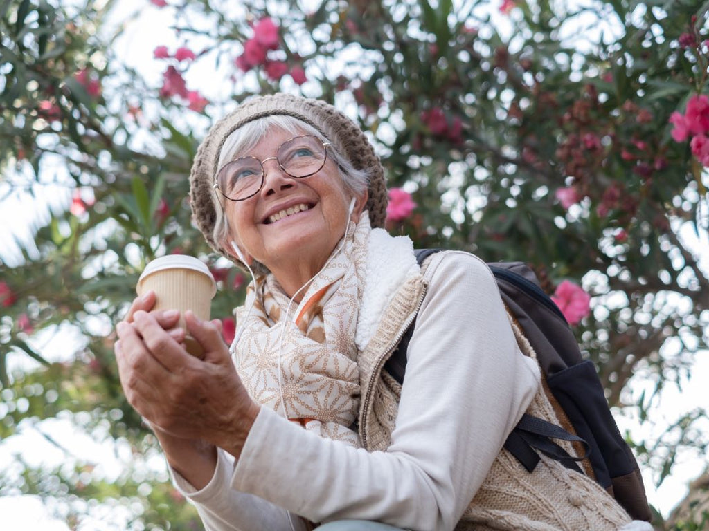 Happy elderly woman having coffee outdoors
