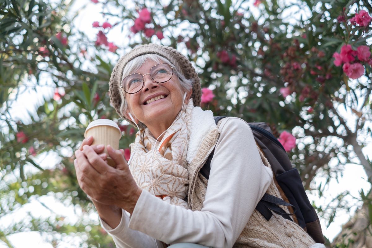 Happy elderly woman having coffee outdoors