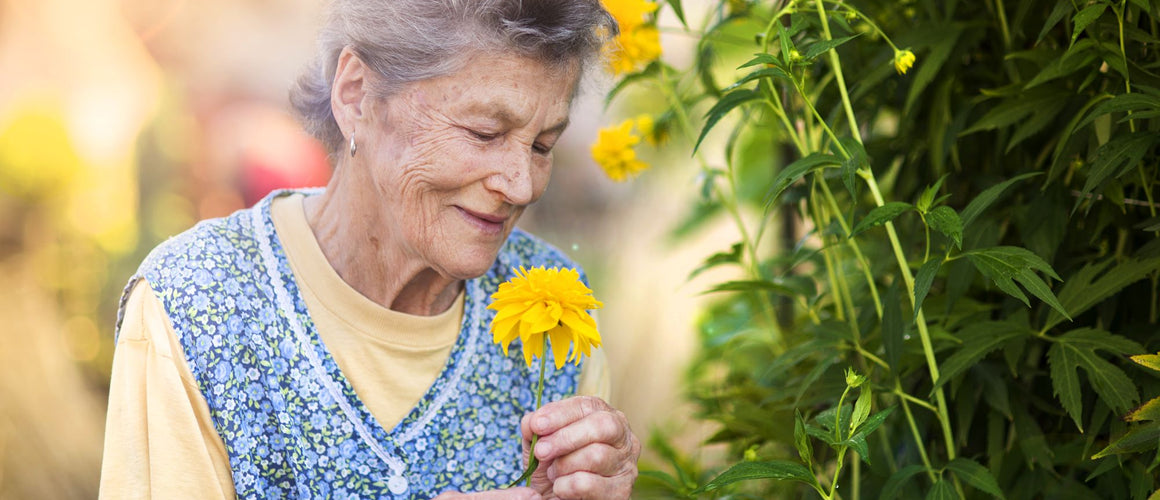 Elderly woman with a colourful flower in her garden