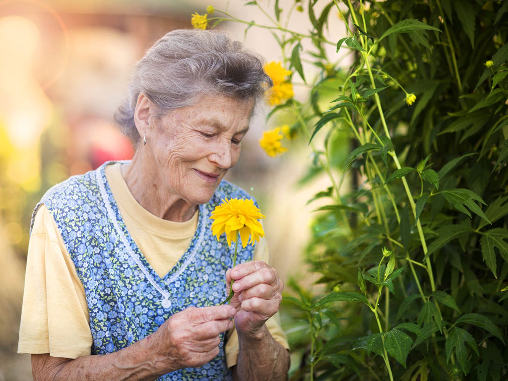 Elderly woman with a colourful flower in her garden