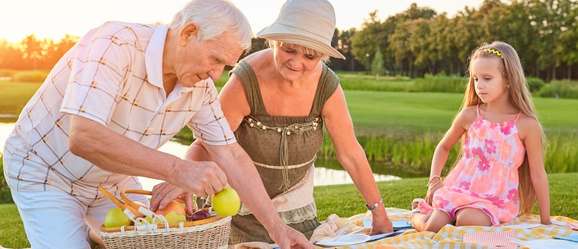 Elderly grandparents having picnic with grandchild in summer