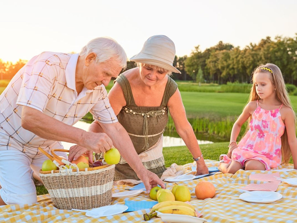 Elderly grandparents having picnic with grandchild in summer