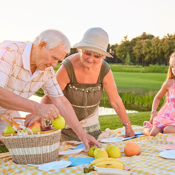 Elderly grandparents having picnic with grandchild in summer