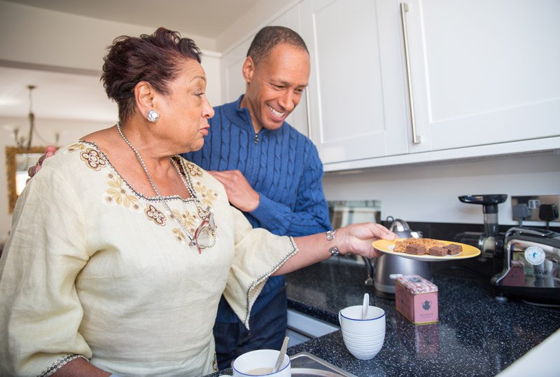 Elderly mother and adult son in kitchen