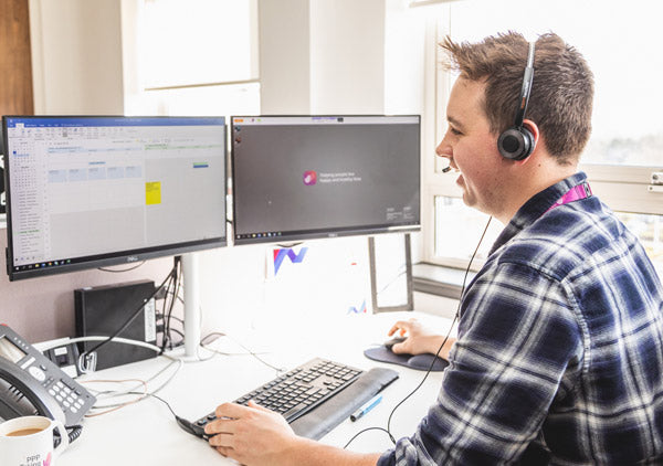 Man working at a desk with two monitors, wearing headphones.