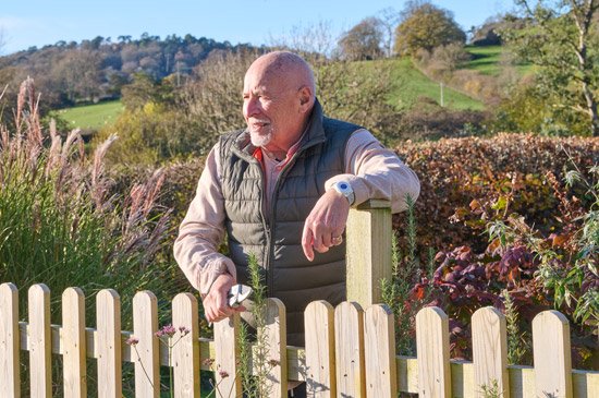 Older man leaning on fence