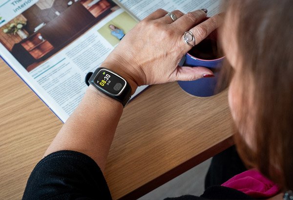 Person using a Dementia Tracker with a magazine open on a table