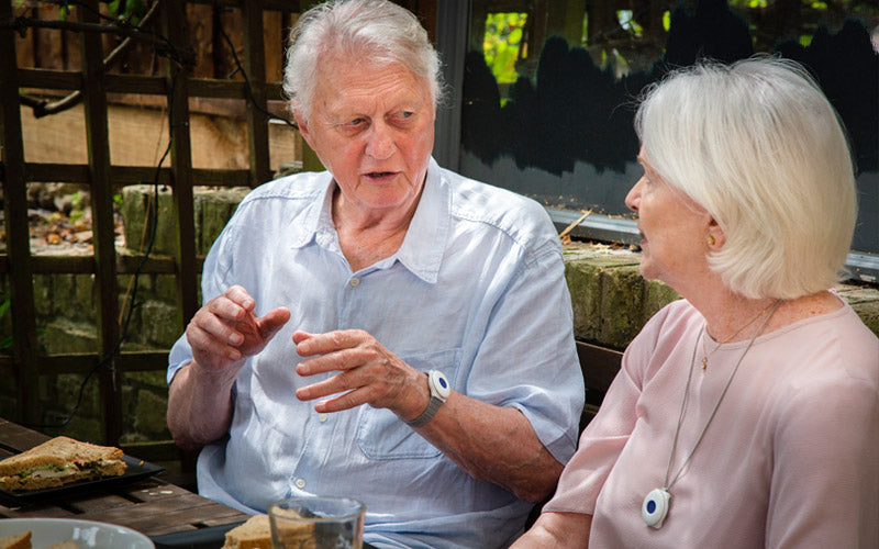 Two elderly people engaged in a conversation outdoors.