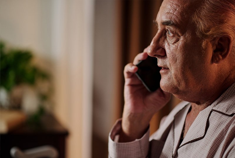 Man talking on a phone with a blurred indoor background