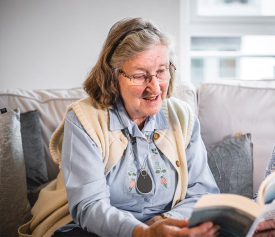 Elderly lady wearing falls alert bracelet and reading
