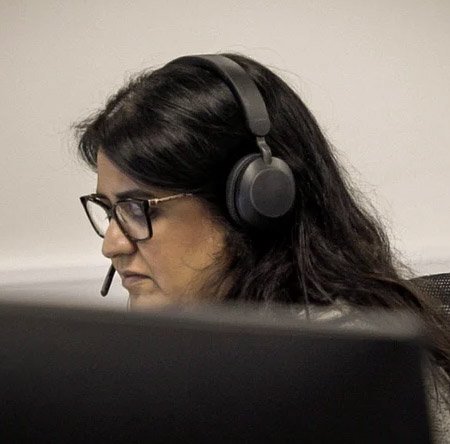 Person wearing headphones and glasses in a neutral setting