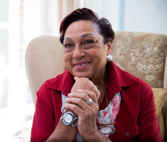 Woman in a red jacket sitting on a couch with a smile