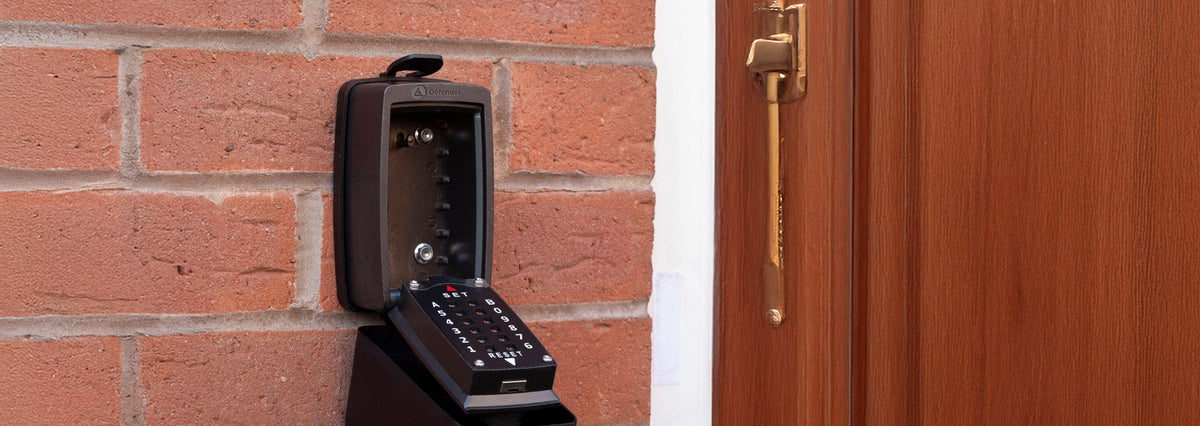Security keypad mounted on a brick wall next to a wooden door