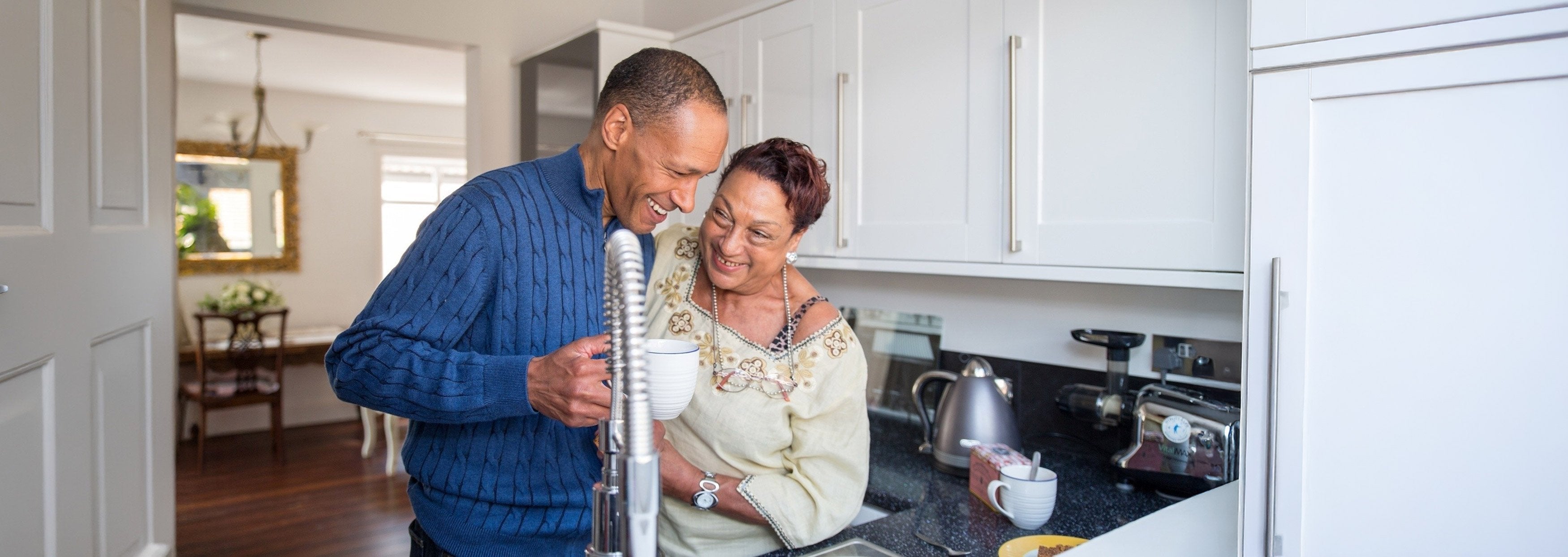 Man and woman in a kitchen looking at a faucet
