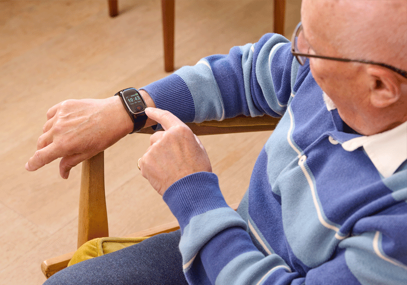 Elderly man pressing emergency button on alarm watch