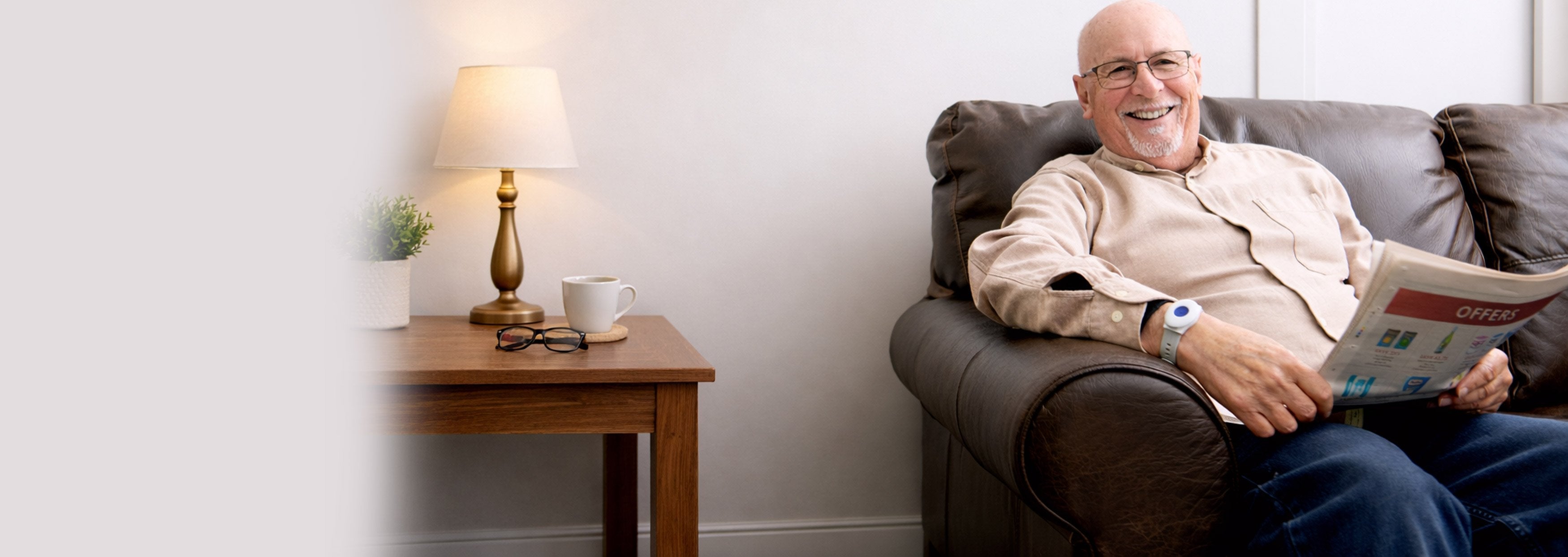 Elderly man sat on sofa wearing personal alarm on wrist