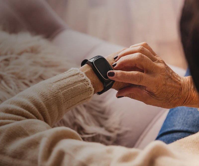 Person adjusting a dementia tracker on their wrist with a blurred background