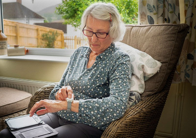 Elderly woman looking at fall alarm