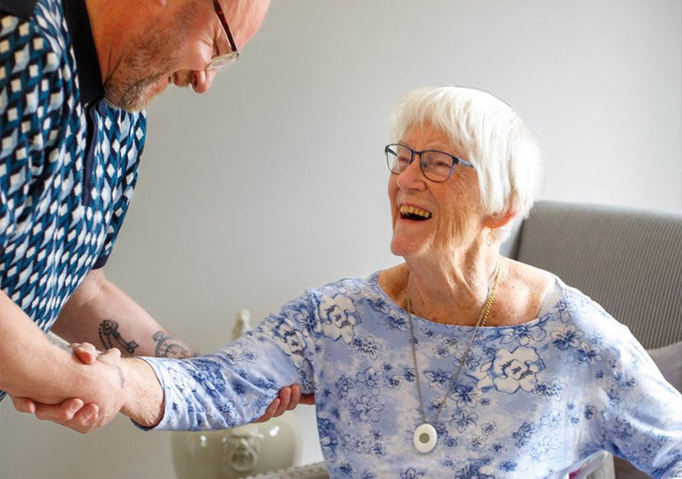 Elderly woman with emergency button being helped up
