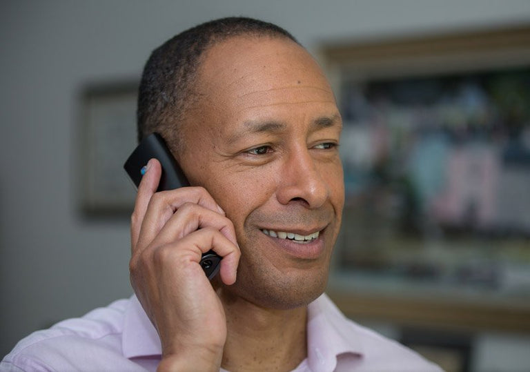 Man talking on a phone with a blurred indoor background