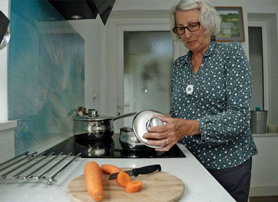 Elderly person in the kitchen wearing panic button