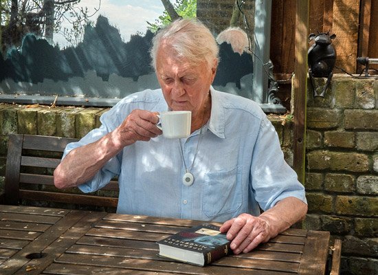 Older man sat in shady garden