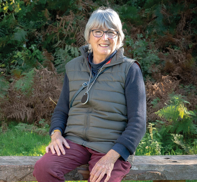 Older woman sitting outdoors with GPS alarm pendant