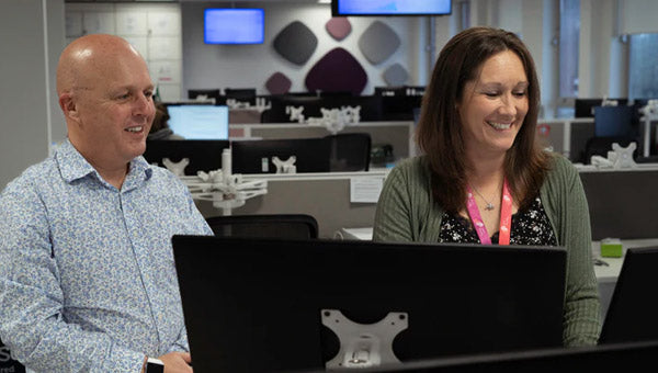 Two people working on a laptop in an office setting