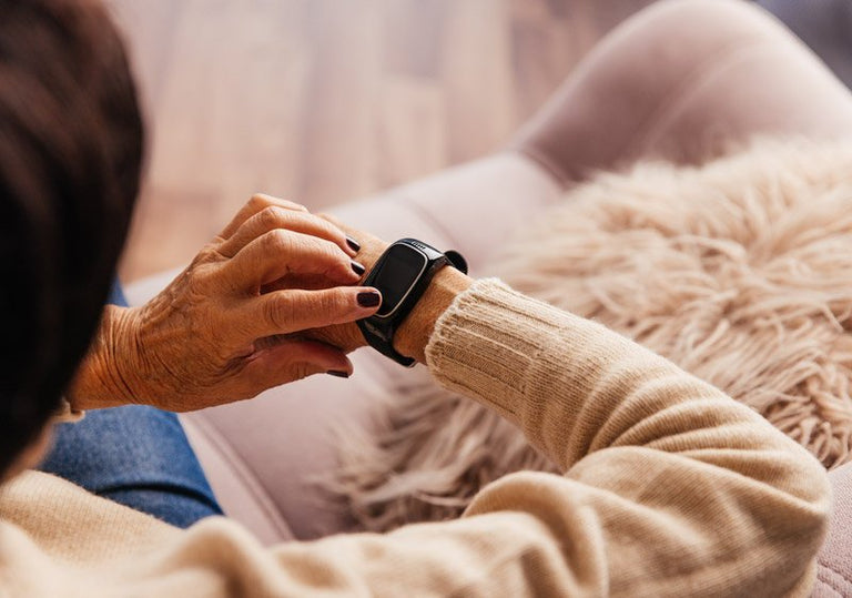 Person wearing a beige sweater using a smartwatch alarm with a blurred background