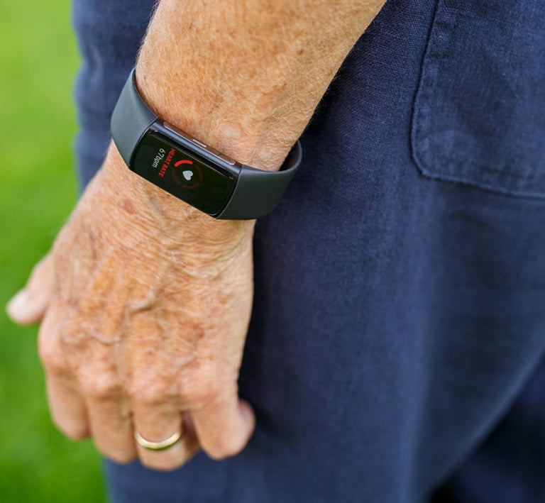 Person wearing a Fitbit smartwatch with a green background