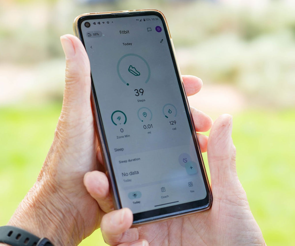 Person holding a smartphone with a fitness app on a blurred outdoor background