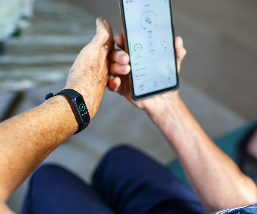 Person holding a smartphone with an app open, wearing a smartwatch on wrist.